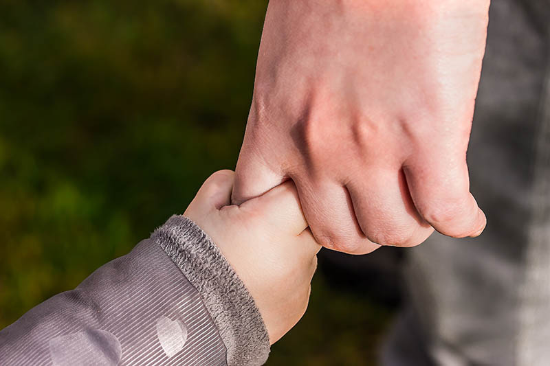 Mano de adulto cogida por la de un pequeño